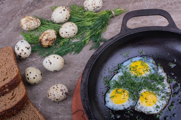 Foto gratuita huevos fritos en una sartén metálica con hierbas.