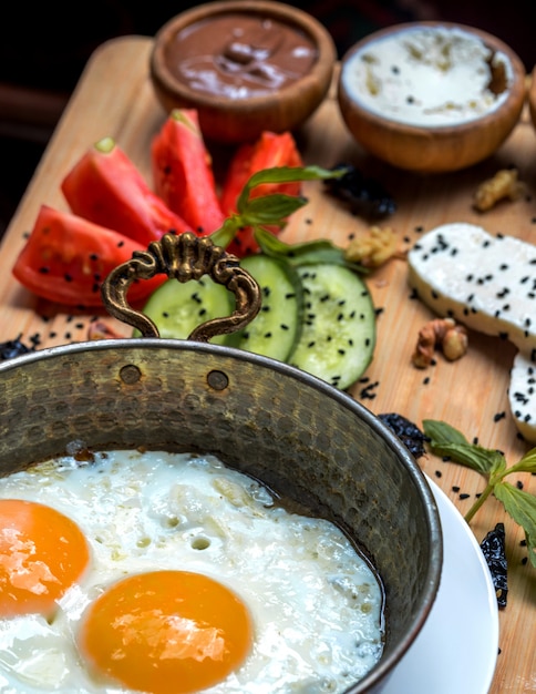 Huevos fritos con verduras sobre tabla de madera