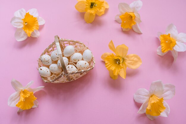 Huevos de gallina blanca en canasta con flores amarillas