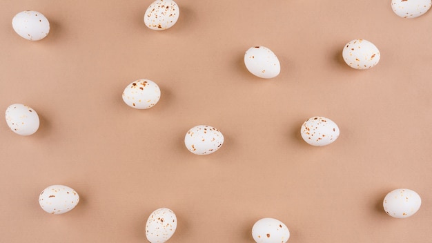 Foto gratuita huevos de gallina blanca esparcidos sobre mesa beige