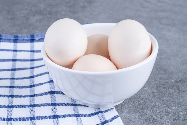 Huevos de gallina blanca fresca en una placa blanca.
