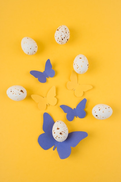 Huevos de gallina blanca con mariposas de papel en mesa