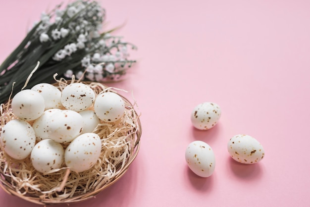 Huevos de gallina blanca en nido con flores