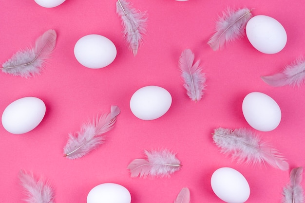 Huevos de gallina blanca con plumas en mesa