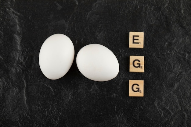 Foto gratuita huevos de gallina blanca sobre una mesa negra.