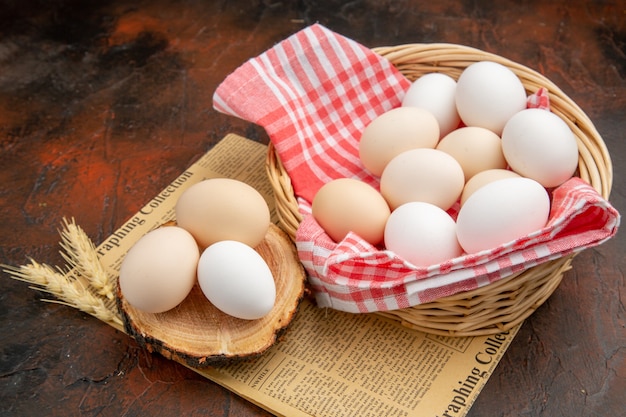 Huevos de gallina blanca vista frontal dentro de la canasta sobre una superficie oscura