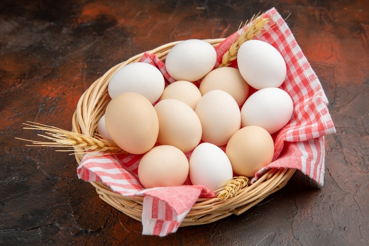 Foto gratuito huevos de gallina blanca vista frontal dentro de la canasta con toalla sobre la superficie oscura