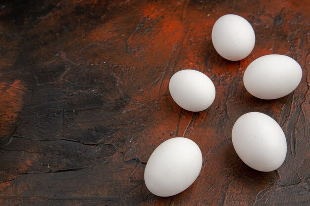 Huevos de gallina blanca vista frontal sobre la superficie oscura