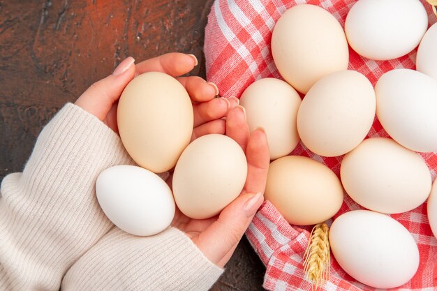 Huevos de gallina blanca vista superior dentro de la canasta con toalla sobre la mesa oscura