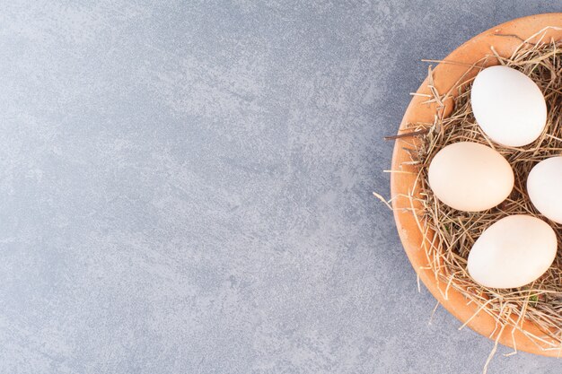 Huevos de gallina blancos crudos frescos en un tazón de madera.