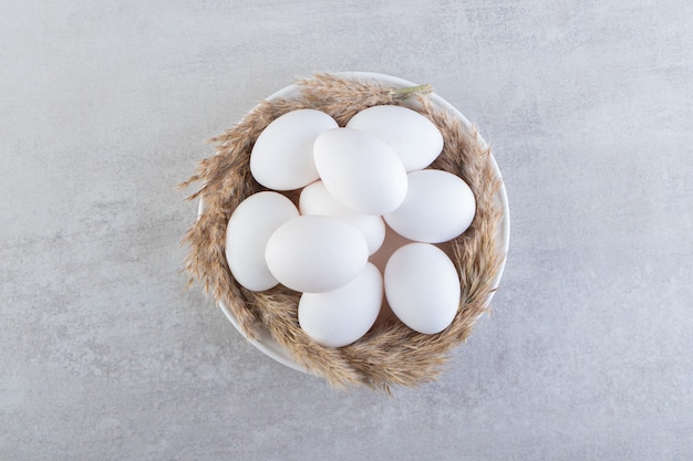 Huevos de gallina blancos frescos crudos colocados sobre una superficie de piedra.