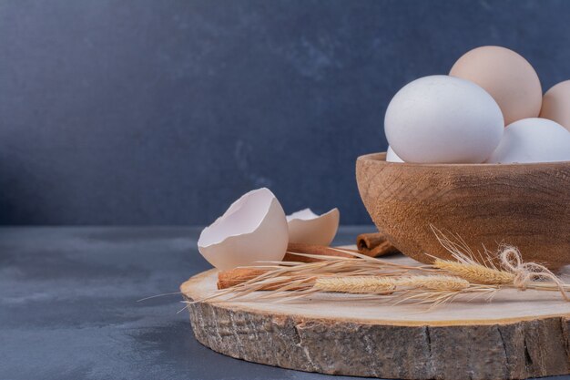 Huevos de gallina con cáscaras de huevo en bandeja de madera
