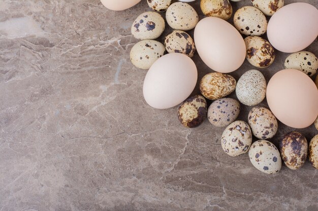 Huevos de gallina y codorniz sobre mármol.