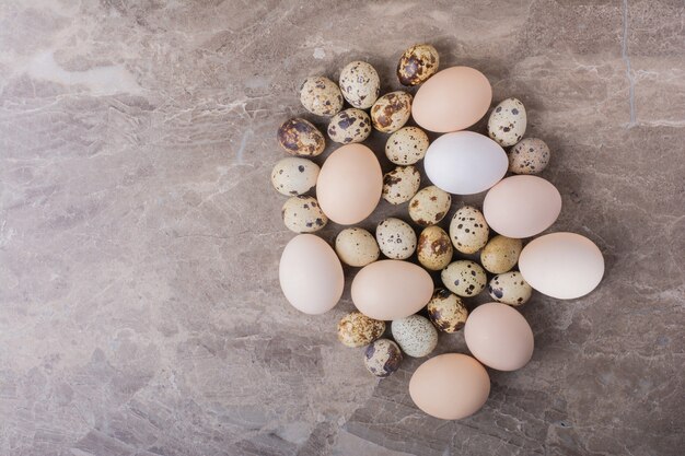 Huevos de gallina y codorniz en la superficie de la piedra