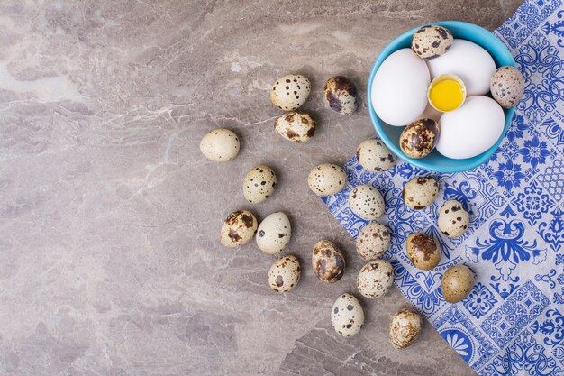 Huevos de gallina y codorniz en una taza azul.