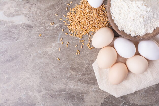 Huevos de gallina con granos de trigo y una taza de harina