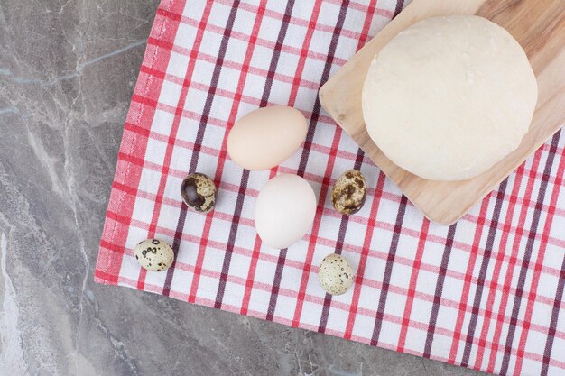 Huevos de gallina con huevos de codorniz y masa sobre mantel. Foto de alta calidad