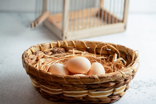 Huevos de gallina orgánicos en canasta en superficie gris.