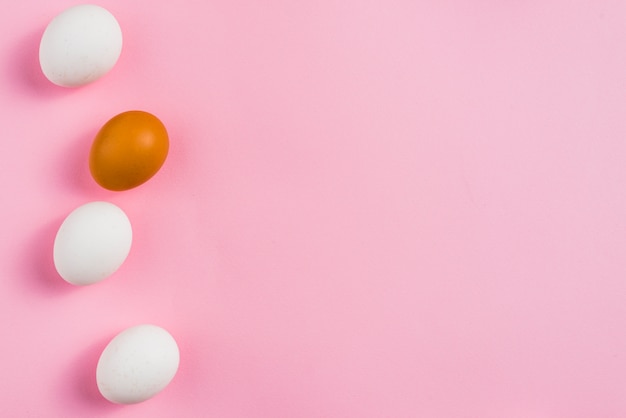 Huevos de gallina pequeños esparcidos sobre mesa rosa