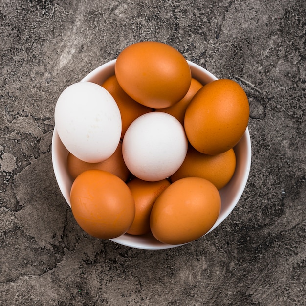 Huevos de gallina en un tazón en mesa gris