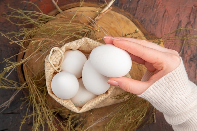 Huevos de gallina de vista superior dentro de la pequeña bolsa con mano femenina