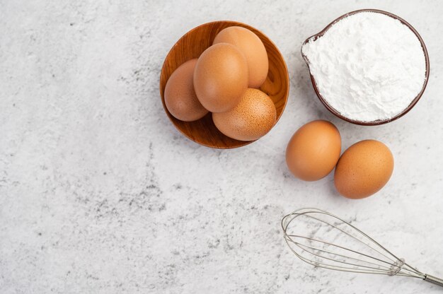 Huevos, harina de tapioca en una taza y batidor de huevos.