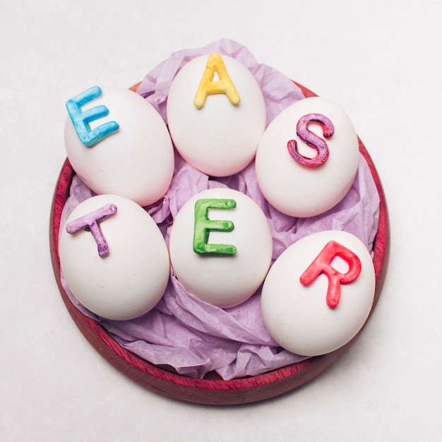 Foto gratuita huevos con letras de pascua en bandeja