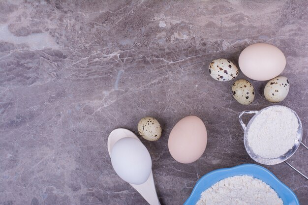 Huevos orgánicos con una taza de harina en la piedra