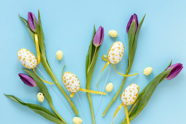 Huevos de Pascua al lado de tulipanes en mesa