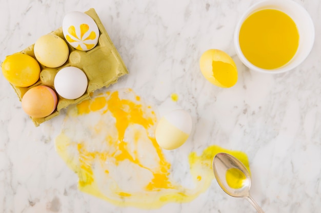 Huevos de Pascua amarillos en un recipiente cerca de una cuchara y tinte líquido