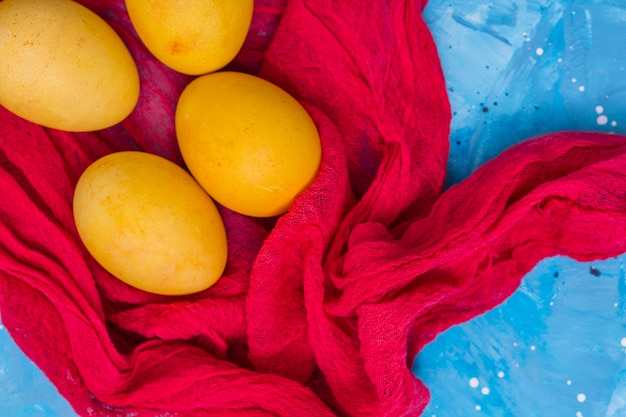 Foto gratuita huevos de pascua amarillos sobre tela roja