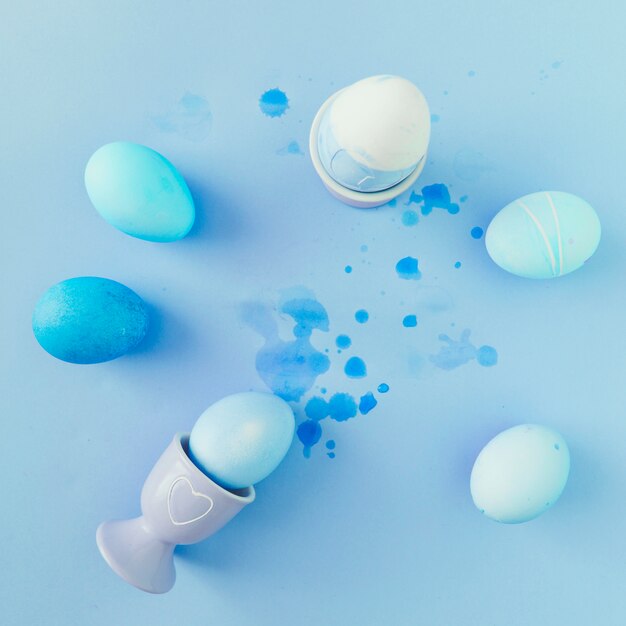 Huevos de Pascua azules y blancos entre salpicaduras de tinte líquido.