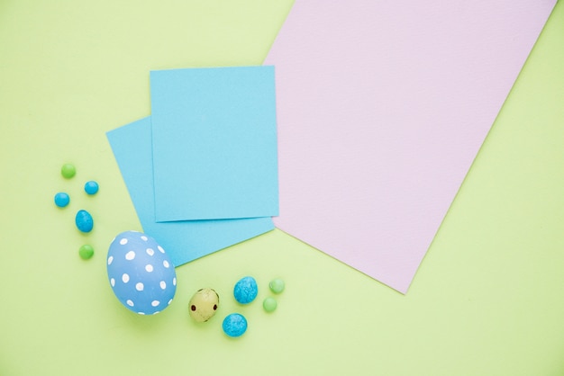 Huevos de Pascua azules con hojas de papel en mesa verde