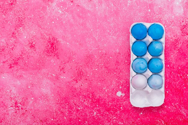 Huevos de Pascua azules en rejilla en mesa rosa