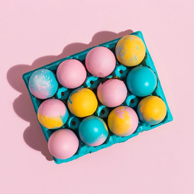 Huevos de Pascua brillantes en estante azul en mesa rosa