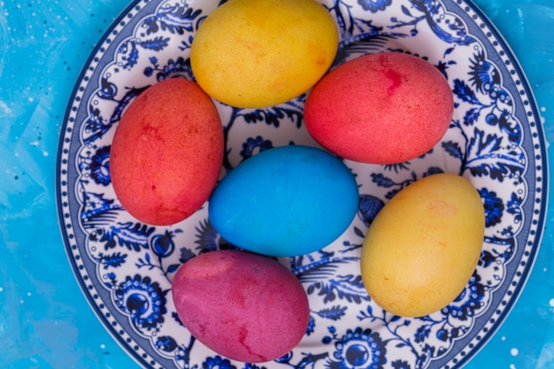 Huevos de Pascua brillantes en placa en mesa azul