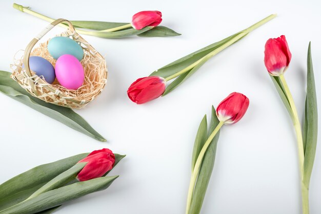 Huevos de Pascua en canasta con tulipanes en mesa