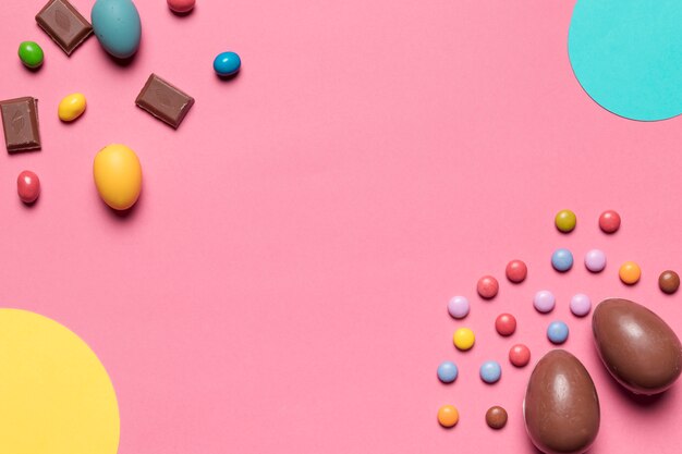 Huevos de Pascua del chocolate y caramelos de la gema con el espacio de la copia para escribir el texto en fondo rosado