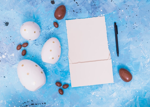 Foto gratuita huevos de pascua de chocolate con papel en blanco.