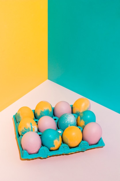 Foto gratuita huevos de pascua coloridos en estante grande en la mesa