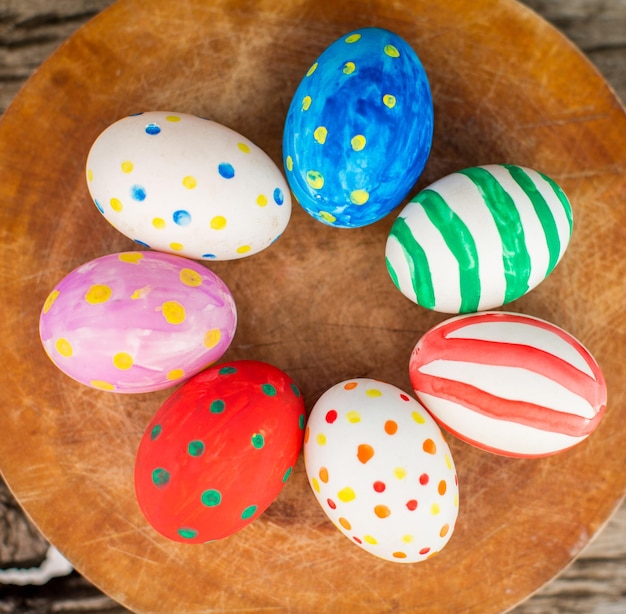 Huevos de pascua coloridos y en mesa de madera