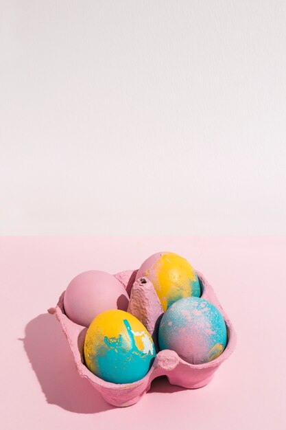 Huevos de Pascua coloridos en pequeño estante en rosa capaz