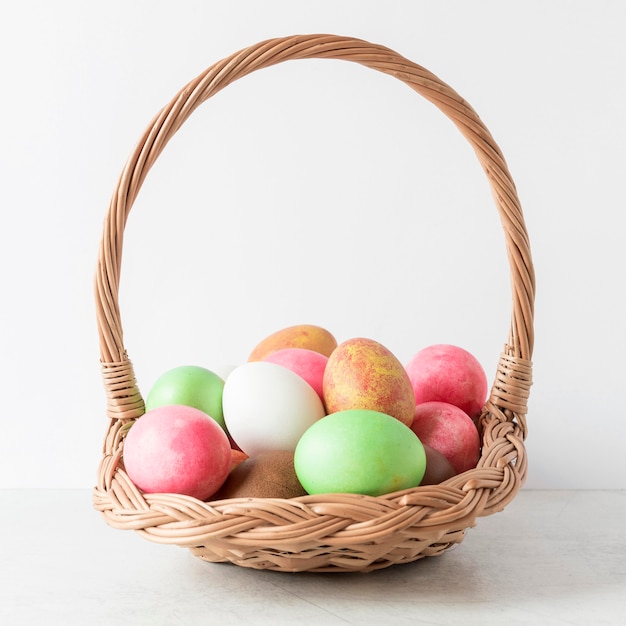 Huevos de Pascua coloridos en vista frontal de la cesta de heno