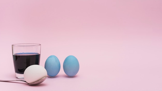 Huevos de Pascua con cuchara y vaso con pintura.