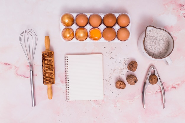 Huevos de Pascua dorados en estante con notebook y utensilios de cocina.