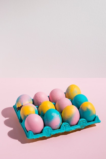 Huevos de Pascua en estante grande en mesa rosa