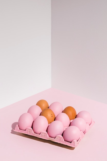 Foto gratuita huevos de pascua en estante rosa en mesa de luz