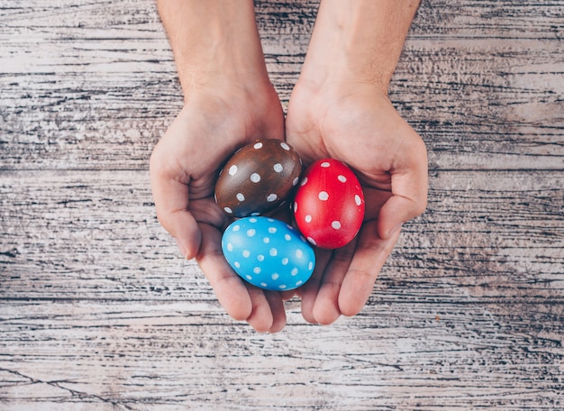 Huevos de Pascua en manos del hombre sobre fondo de madera.