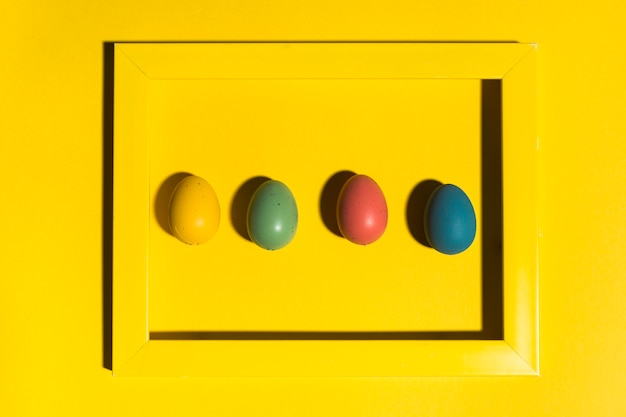 Huevos de Pascua en marco en mesa amarilla