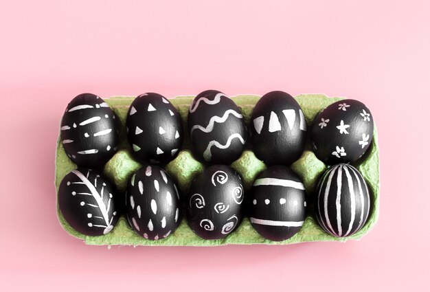 Huevos de Pascua en negro sobre una mesa de color rosa